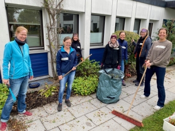 Sechs Roche Mitarbeiter halten Gartengeräte in den Händen und machen unseren Garten winterfest